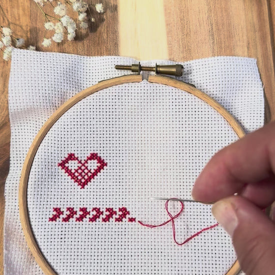 Bee magnetic needle minder in use, showing how the magnets attach securely through cross stitch or embroidery fabric and hold your needle safely while stitching.