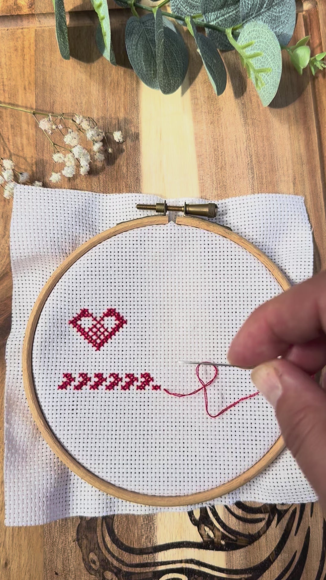 Bee magnetic needle minder in use, showing how the magnets attach securely through cross stitch or embroidery fabric and hold your needle safely while stitching.