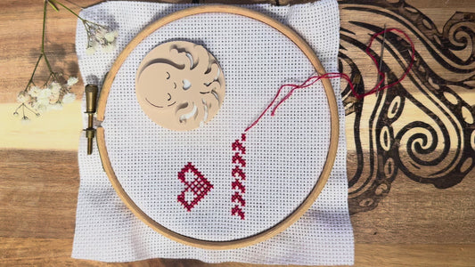 Sleeping Octopus magnetic needle minder in use, showing how the strong magnets attach securely through cross stitch or embroidery fabric and hold your needle safely in place while stitching.
