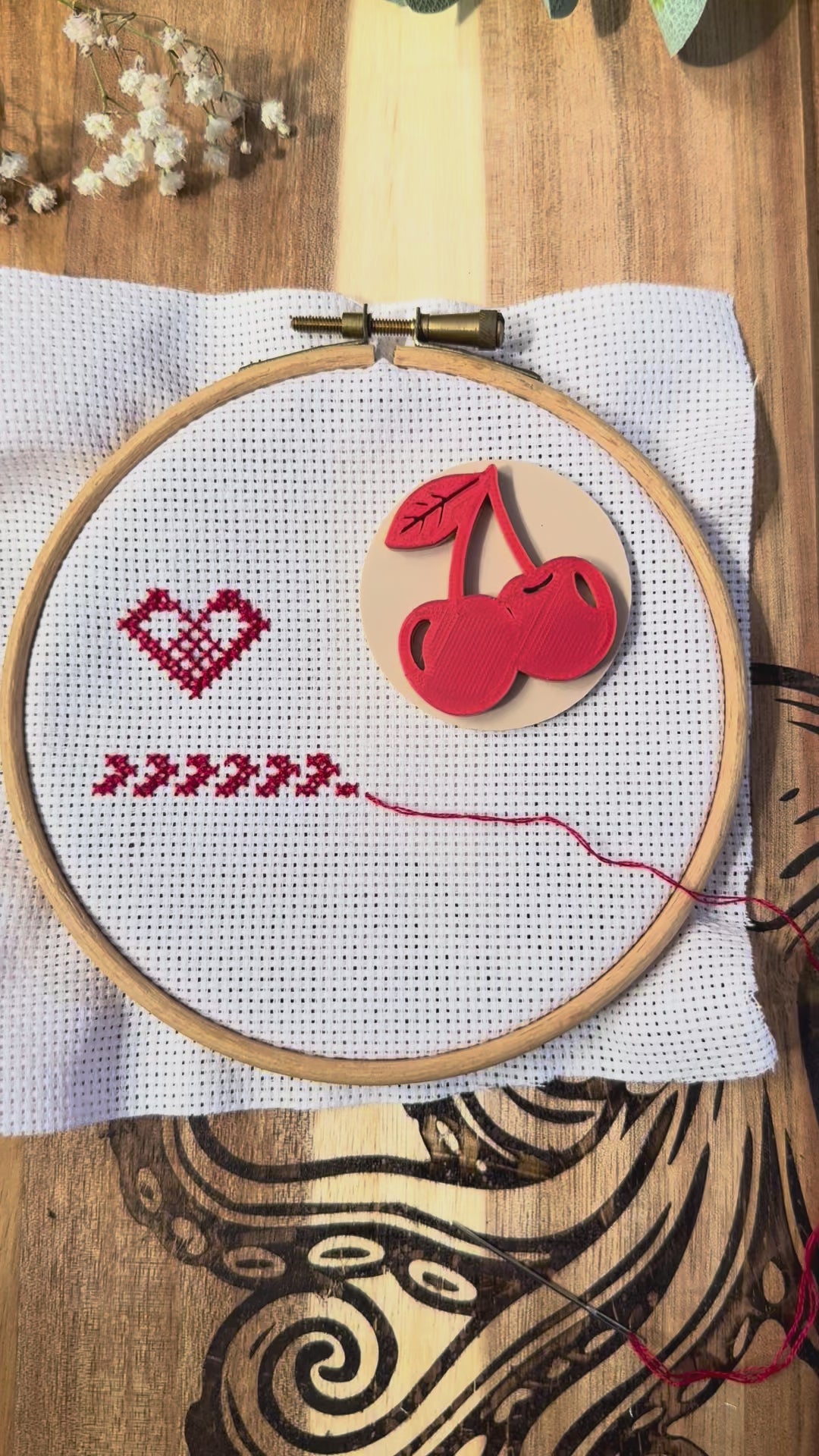 Cherry magnetic needle minder in use, showing how the strong magnets attach securely through cross stitch or embroidery fabric and hold your needle safely in place while stitching.